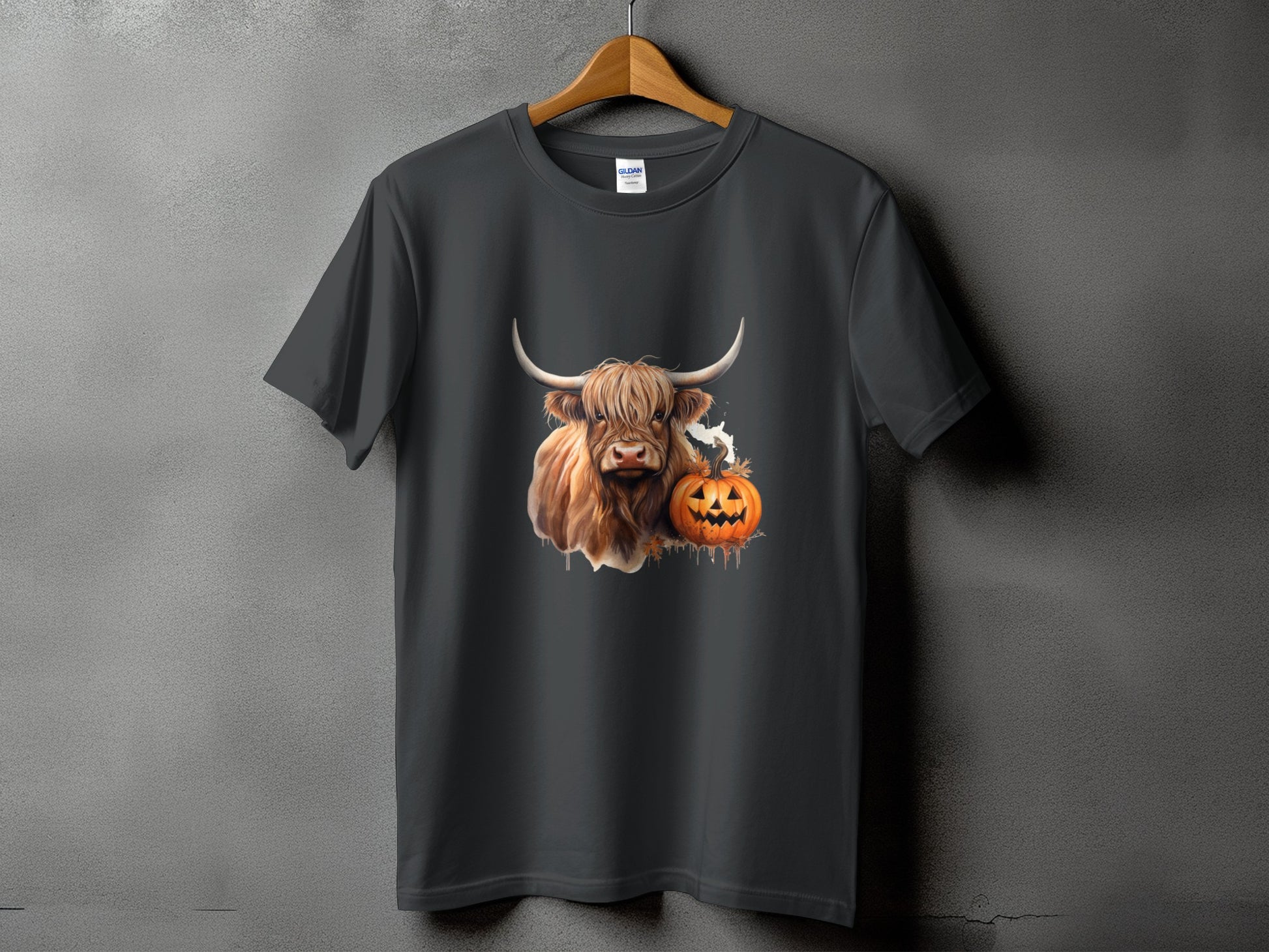 Highland cow with pumpkin and ghost graphic on a dark grey t-shirt.