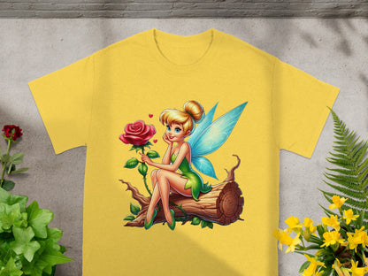 Tinkerbell sitting on a log with a rose, on a yellow t-shirt.
