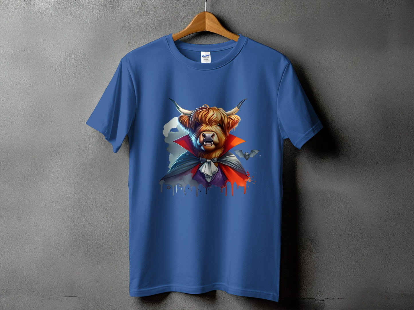 Highland cow dressed as a vampire with bats on a blue t-shirt.