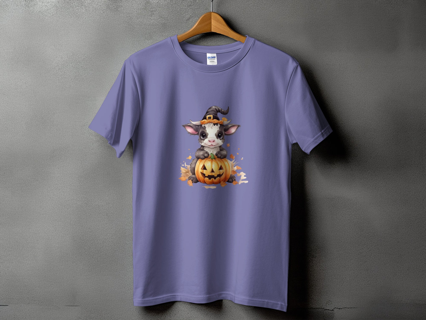 Purple t-shirt with a baby cow wearing a witch hat on a pumpkin.