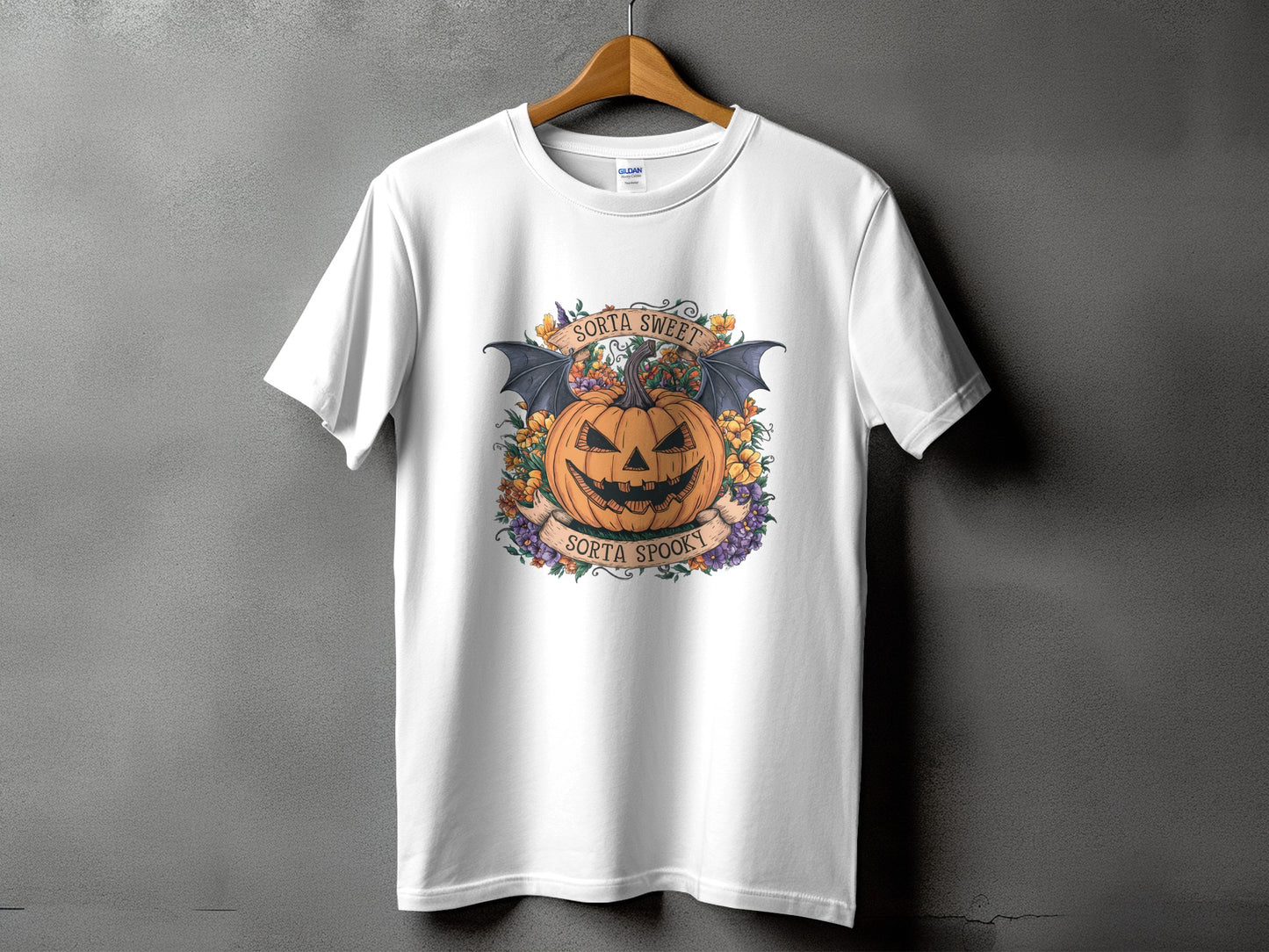White t-shirt with a Halloween design featuring a pumpkin, bats, flowers, and text.