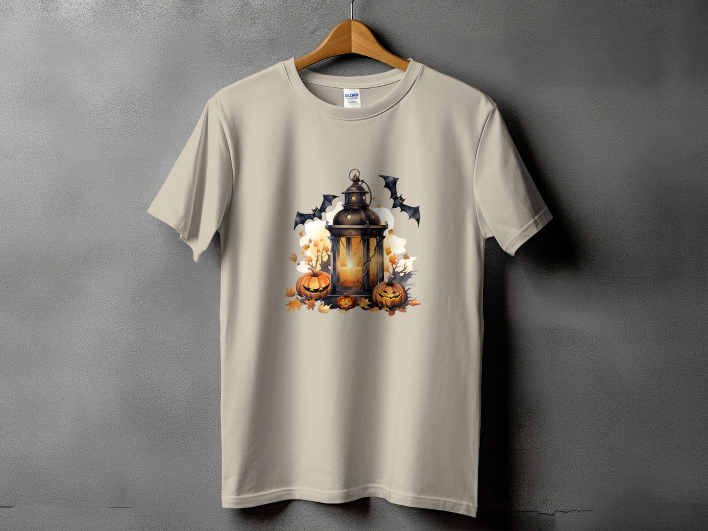 Light tan t-shirt with Halloween graphic featuring a lantern, pumpkins, and bats.