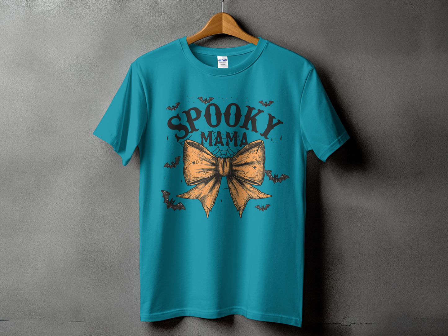 Teal t-shirt with "Spooky Mama" text and an orange bow with bats.
