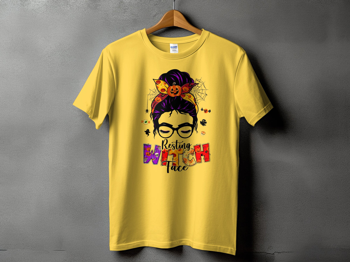 Yellow t-shirt with "Resting Witch Face" Halloween graphic and messy bun.