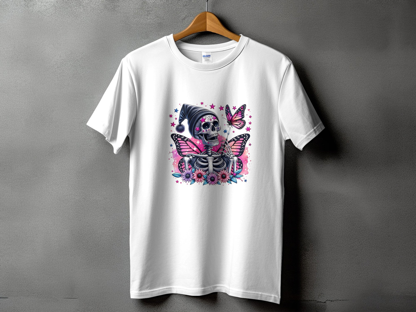 White t-shirt with skeleton wearing a hat and butterfly wings, surrounded by flowers and stars.