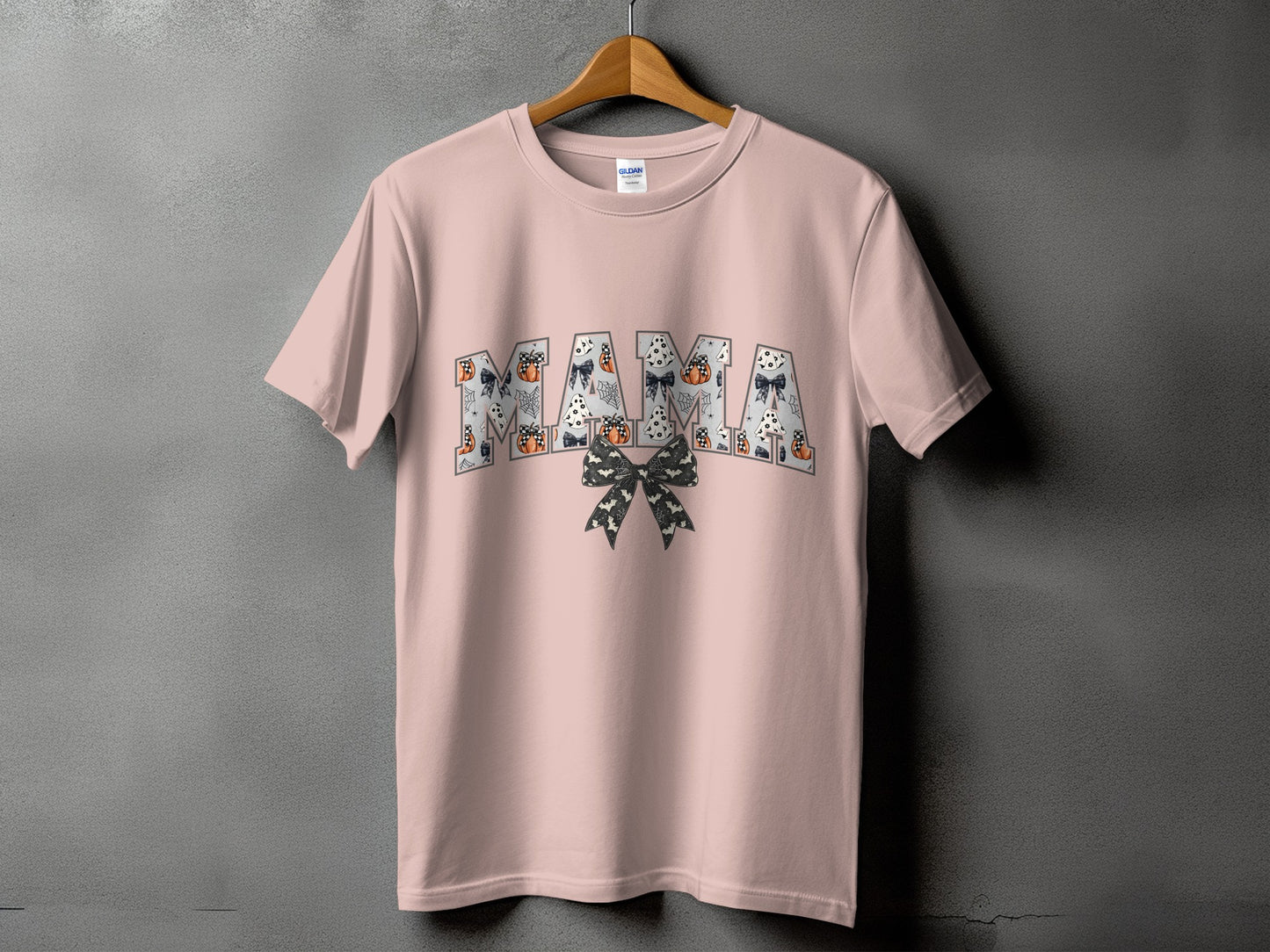Pink t-shirt with "MAMA" text featuring Halloween motifs and a bow.