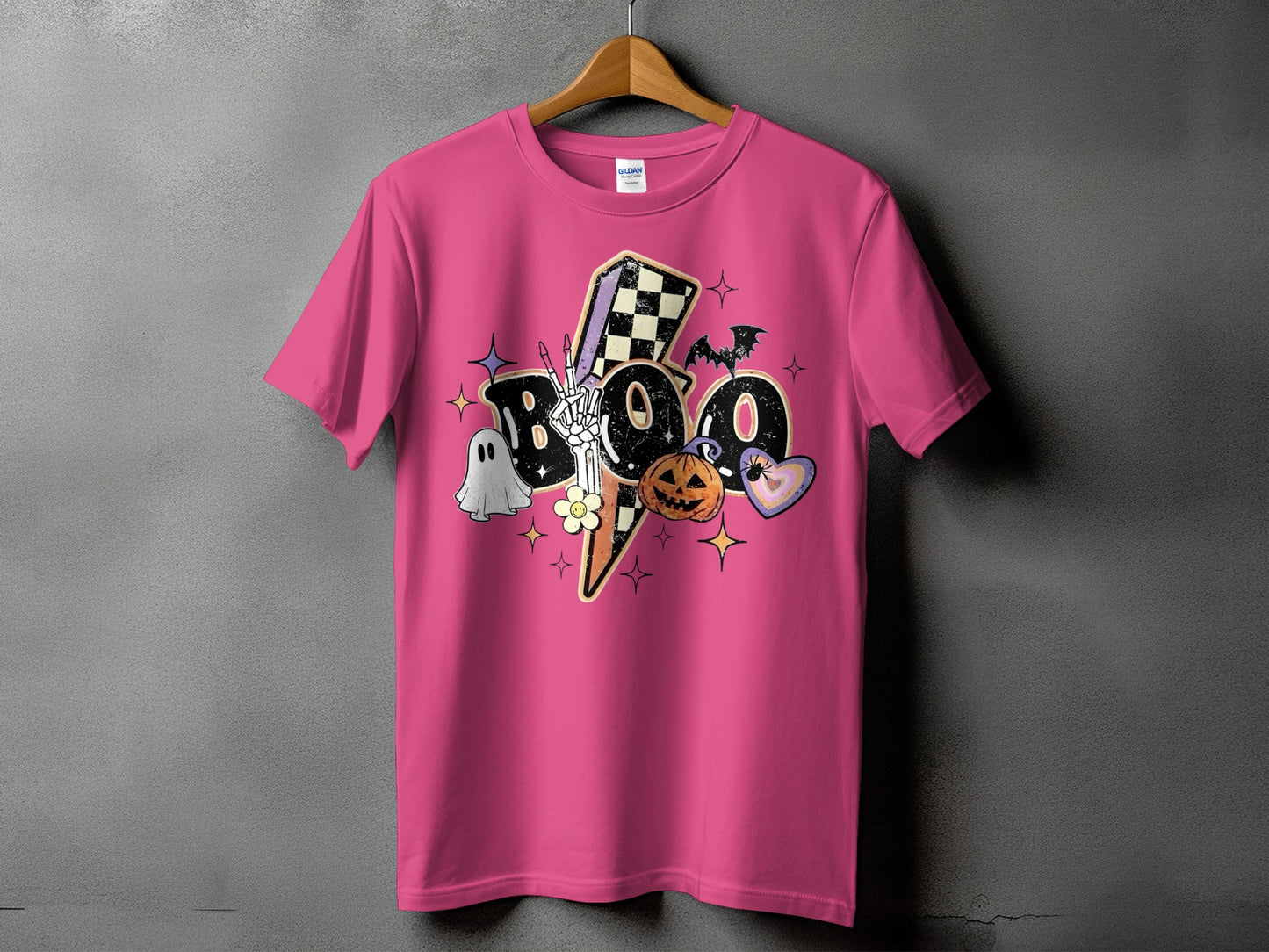 Pink t-shirt with "BOO" Halloween graphic featuring ghost, skeleton hand, pumpkin, and bat.