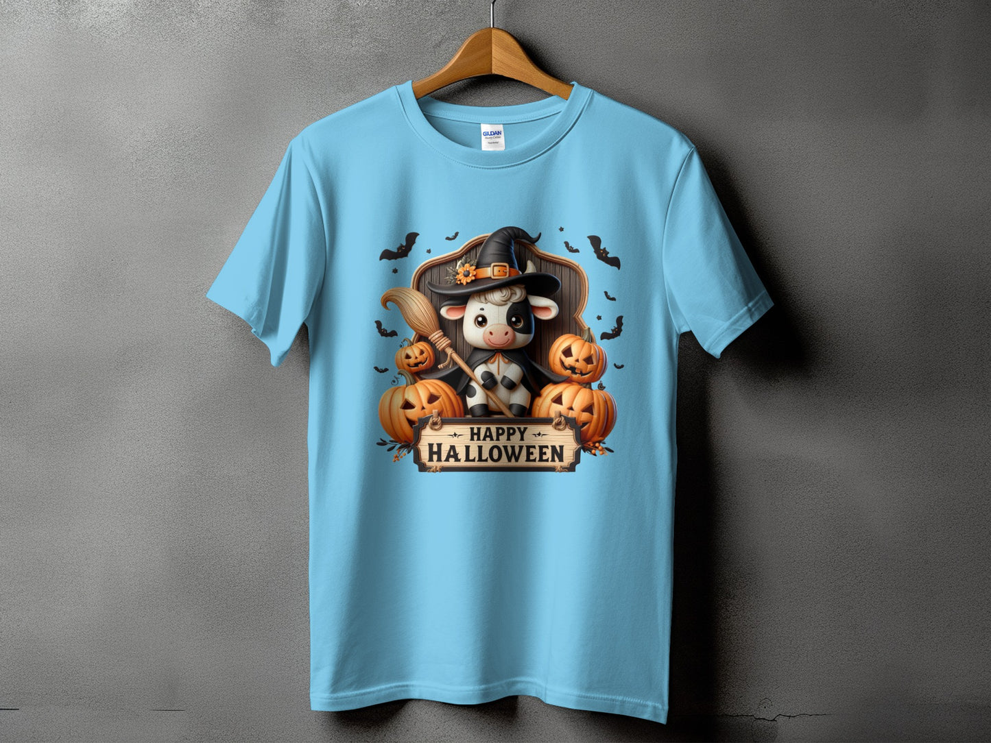 Light blue t-shirt with a Halloween graphic of a cow in a witch hat and pumpkins.