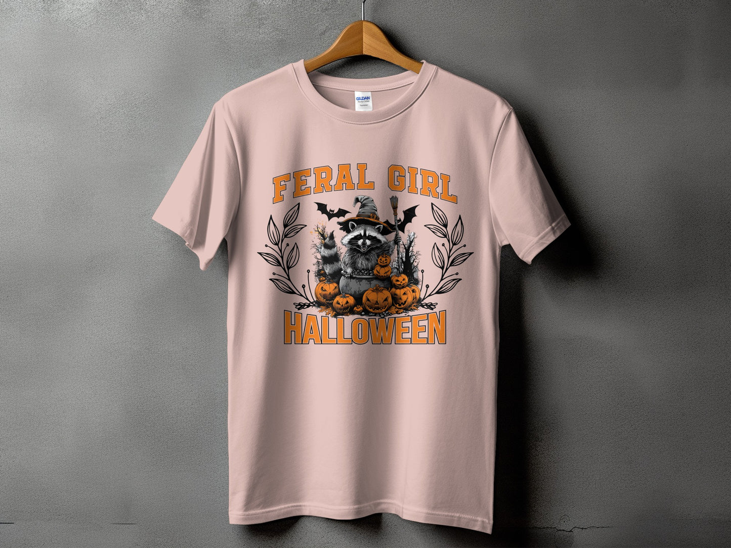 "Feral Girl Halloween" graphic on a pink t-shirt with a raccoon and pumpkins.