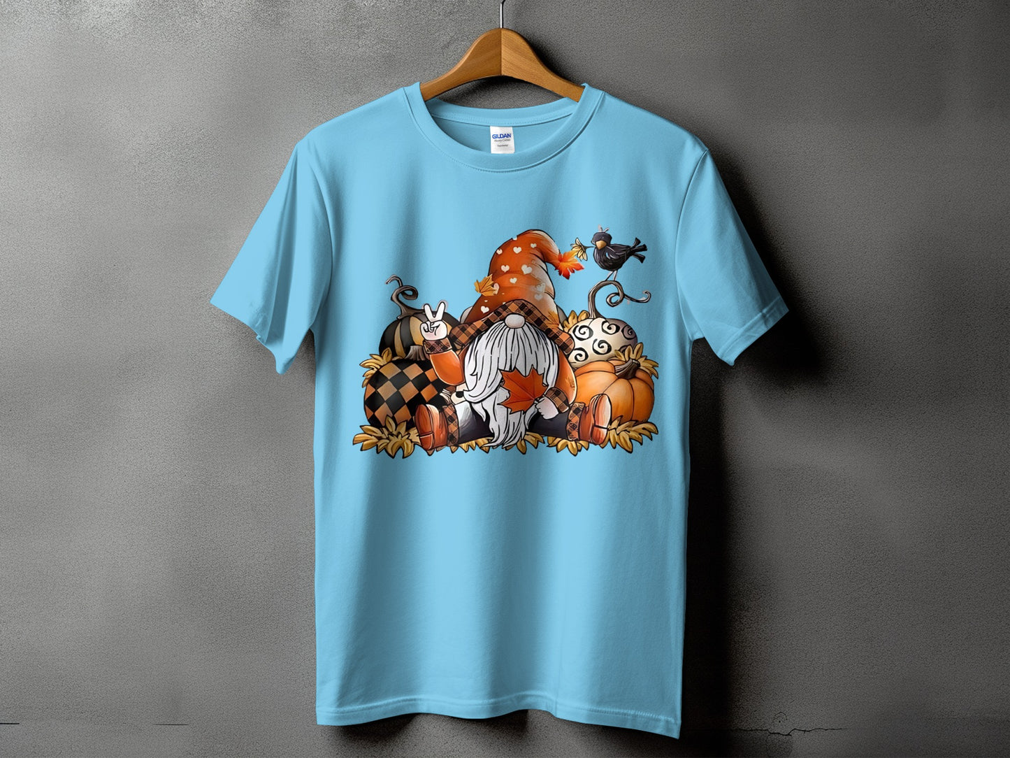 Light blue t-shirt with a fall gnome graphic surrounded by pumpkins and leaves.