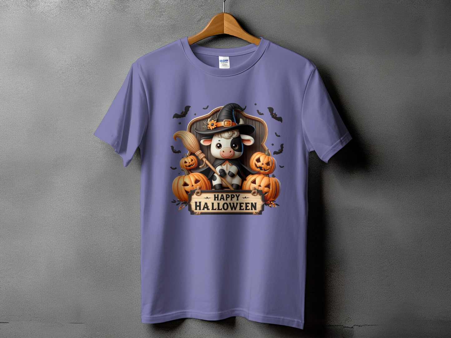 Purple t-shirt with a cow wearing a witch hat and holding a broom with pumpkins.