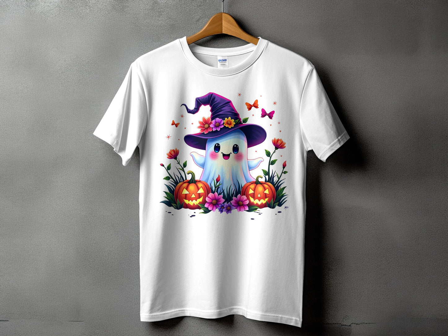 White t-shirt with cartoon ghost in witch hat, pumpkins, and flowers.