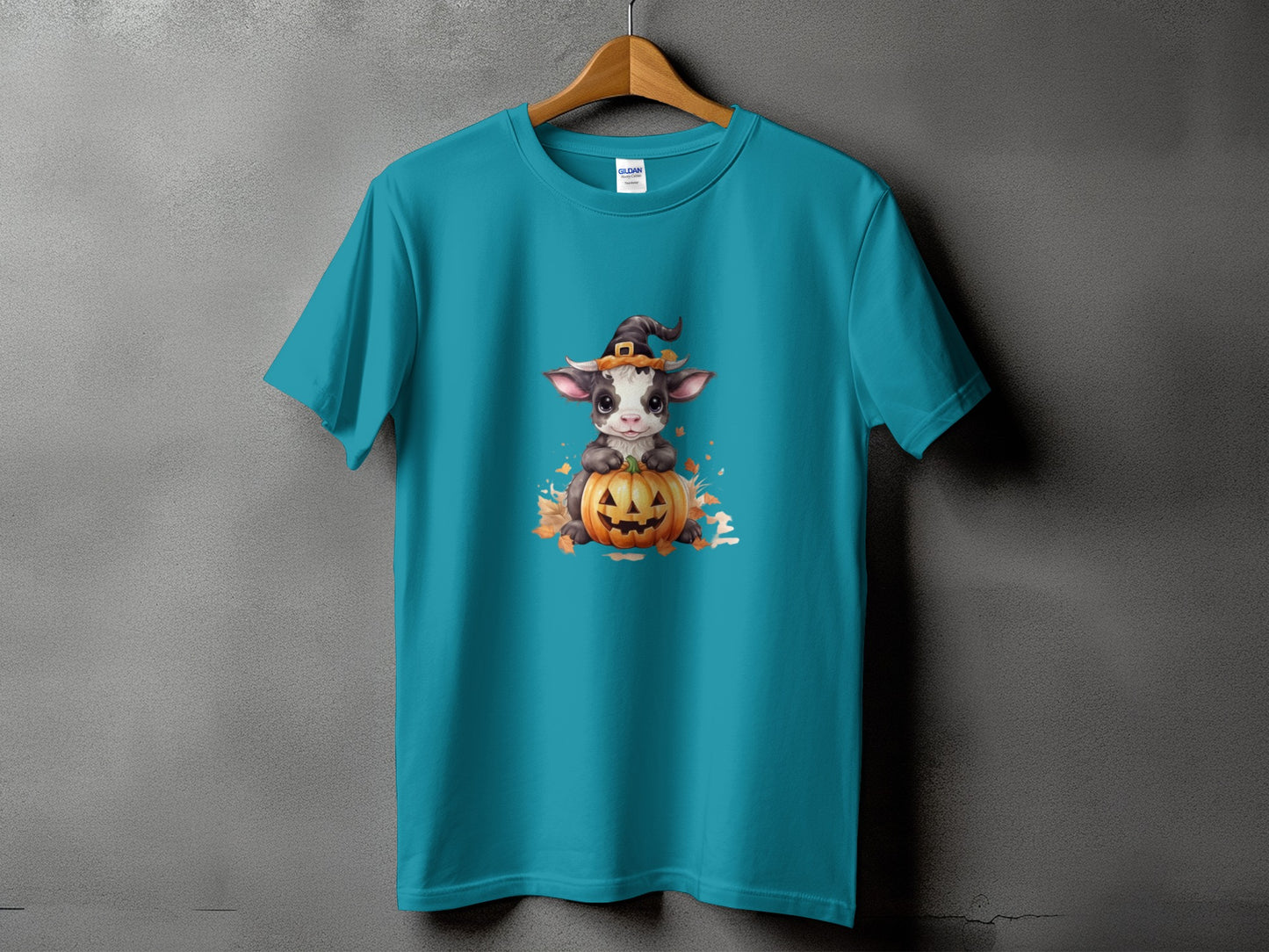 Teal t-shirt with a Halloween graphic of a cow on a pumpkin.