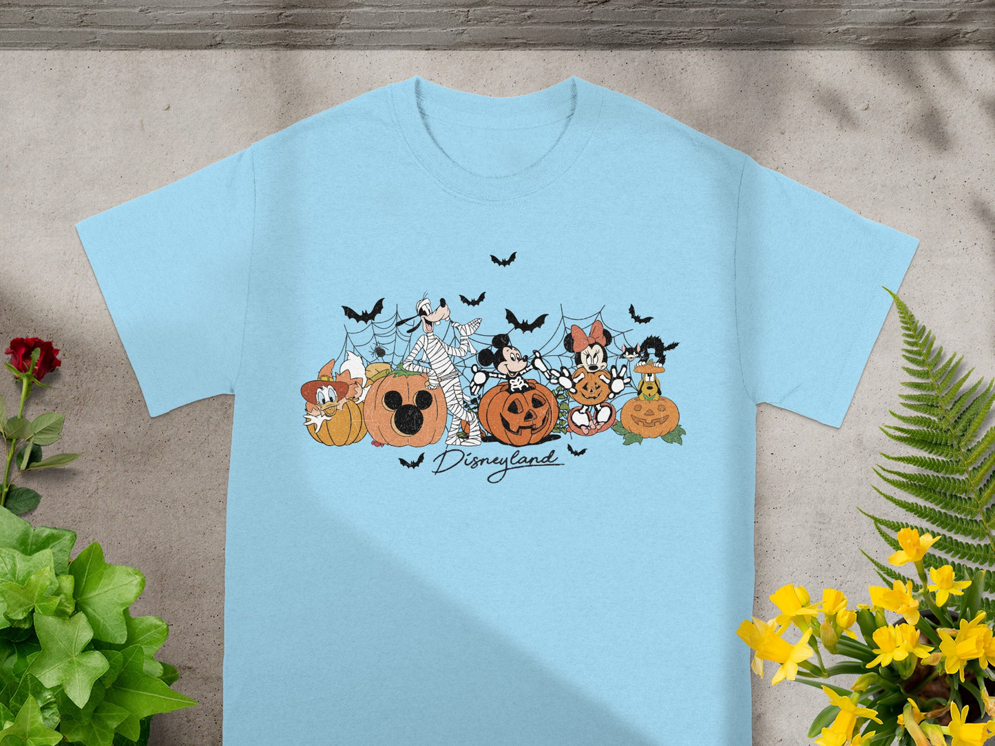 Light blue t-shirt featuring Disney characters in Halloween costumes with pumpkins and bats.