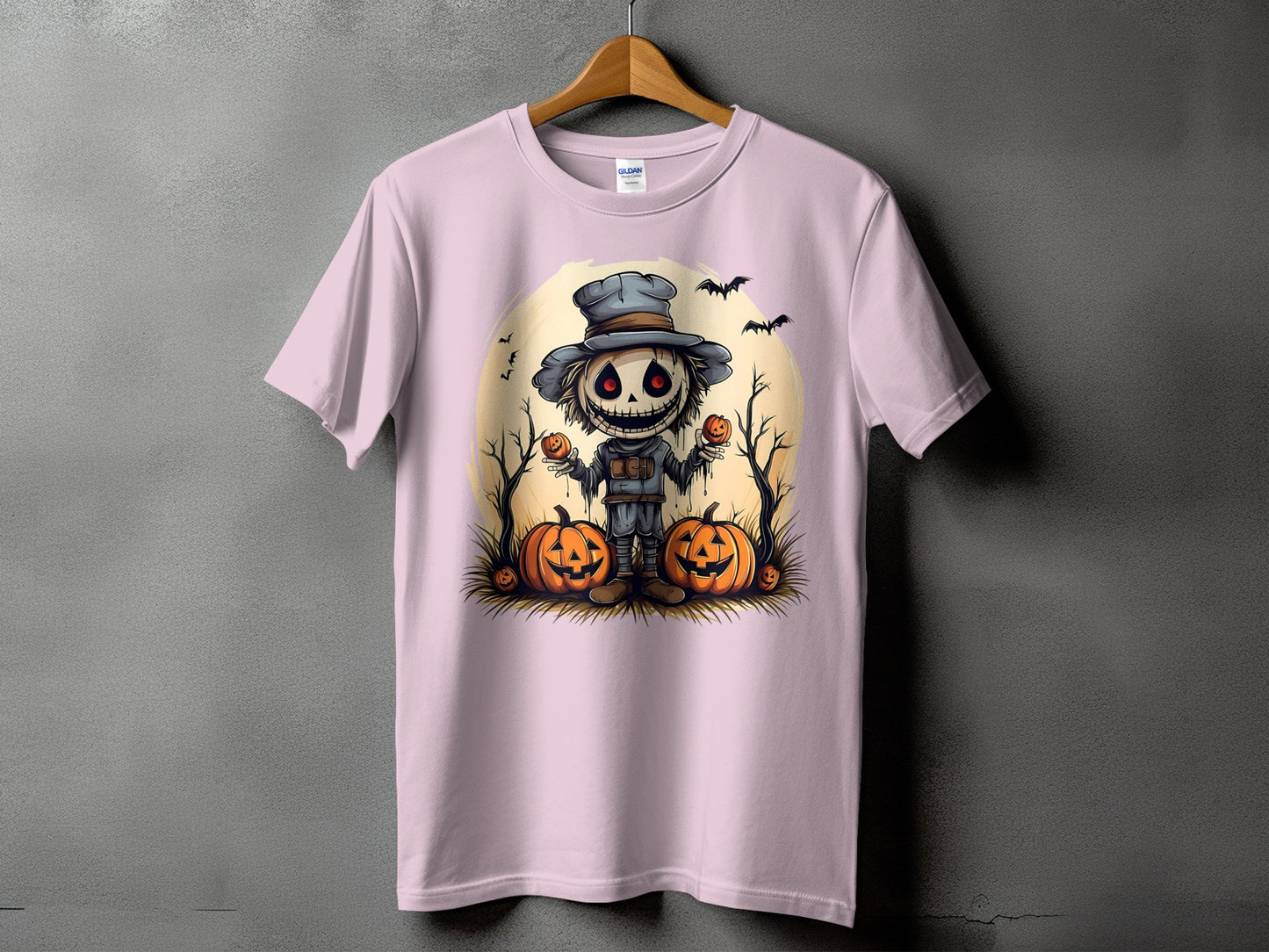 Scarecrow with pumpkins, bats, and moon design on a pink t-shirt.