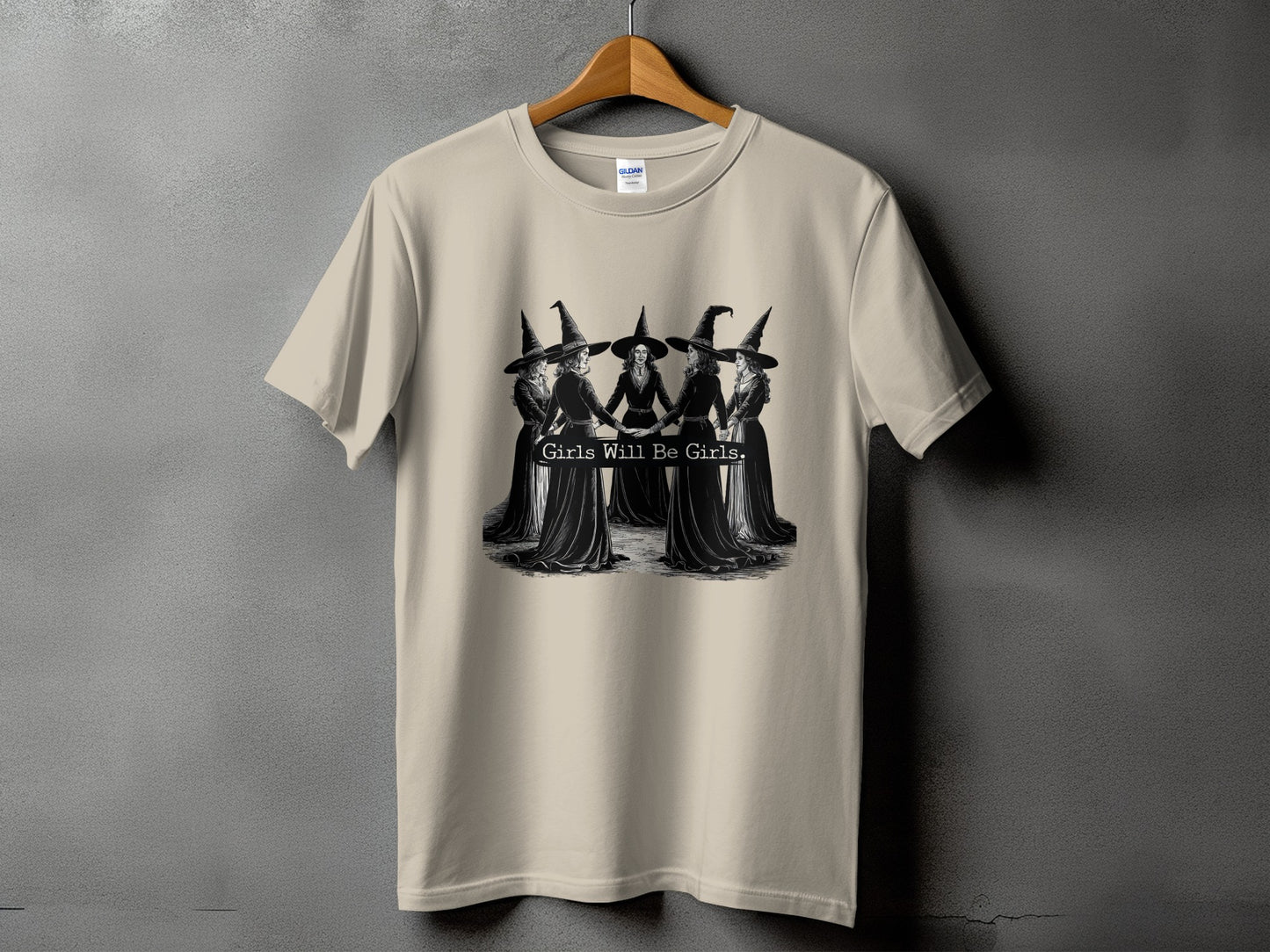 Light tan t-shirt with a graphic of five witches holding hands and the text "Girls Will Be Girls."