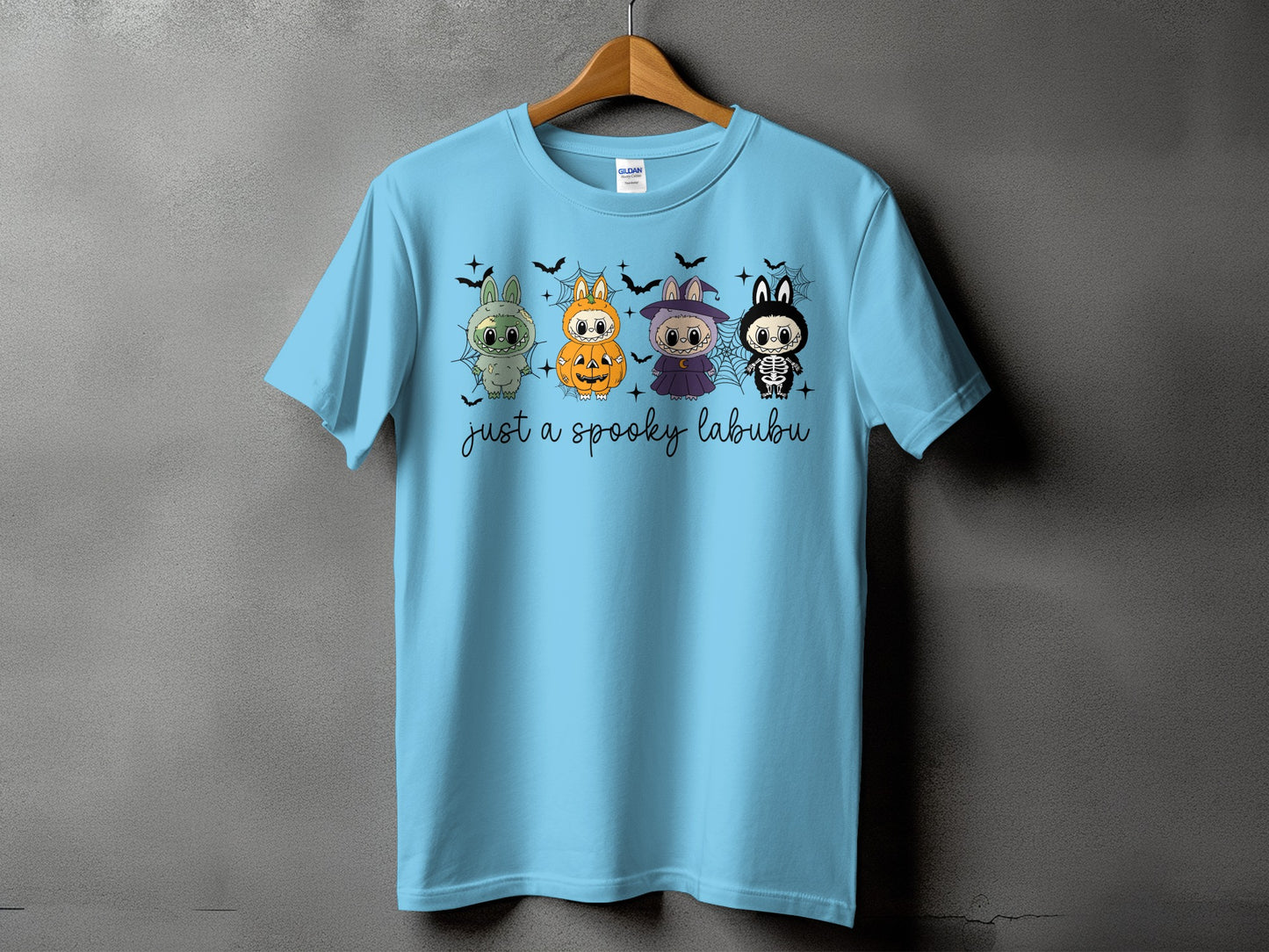 Light blue t-shirt with four cartoon labu characters in Halloween costumes and text.