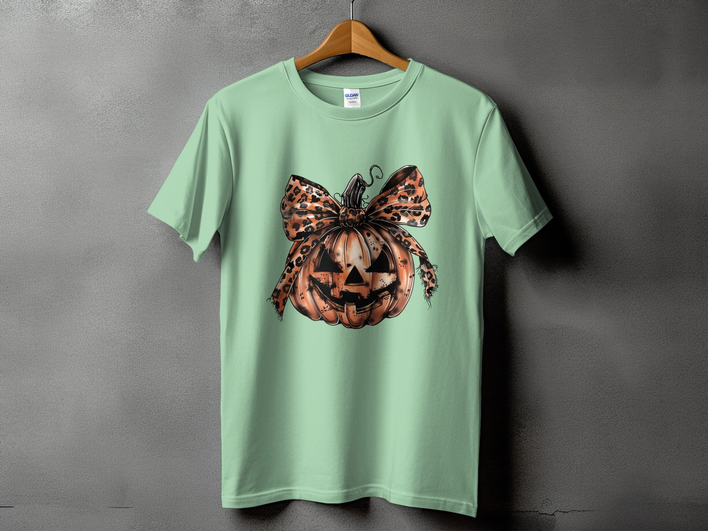 Light green t-shirt with a jack-o'-lantern and leopard print bow graphic.