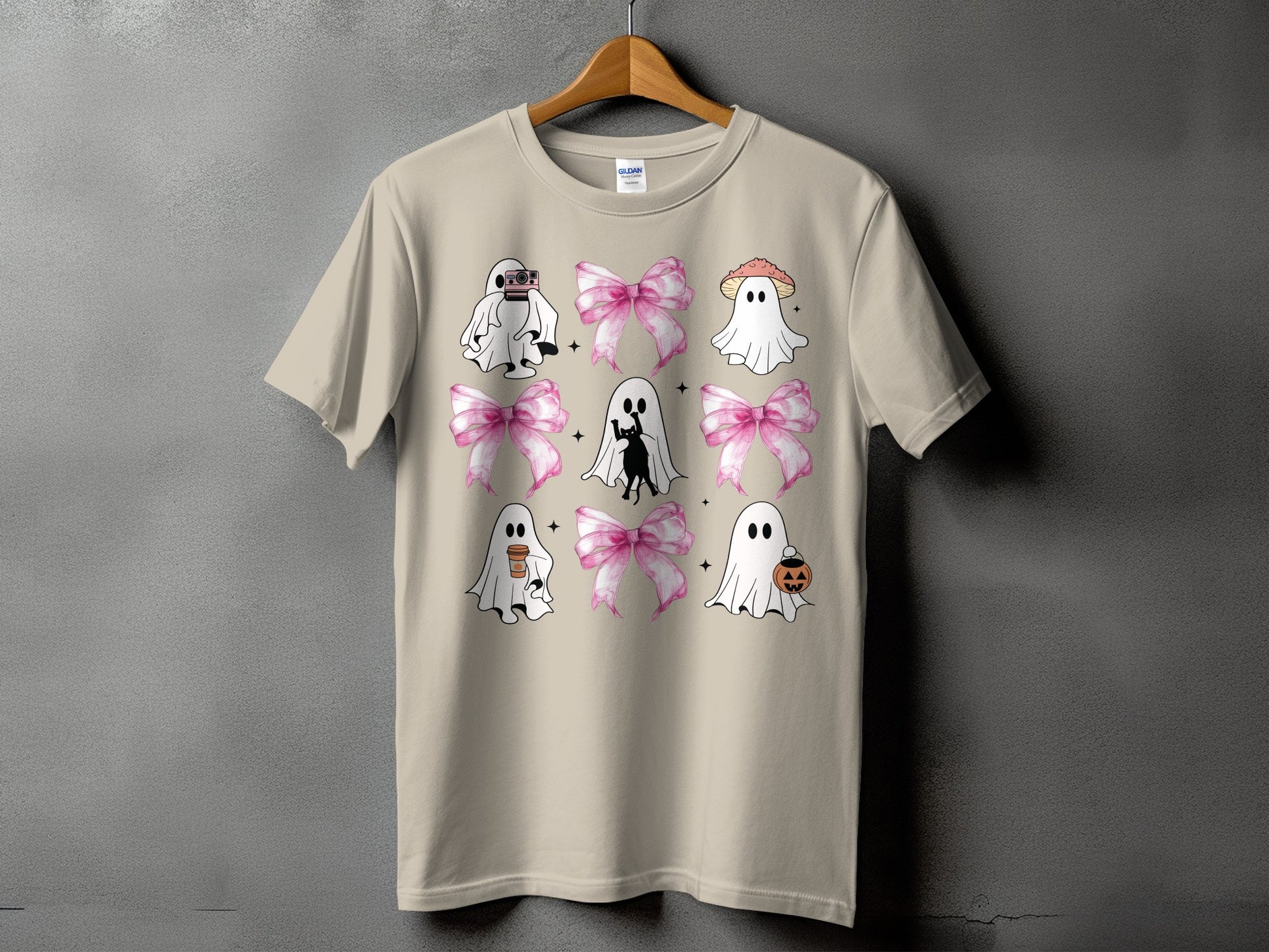 Tan t-shirt with a grid of cute ghosts, pink bows, and Halloween motifs.