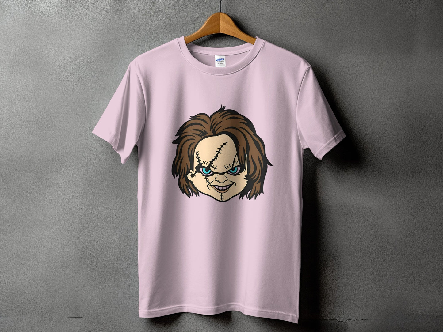 Pink t-shirt with a cartoon illustration of Chucky's face and stitches.
