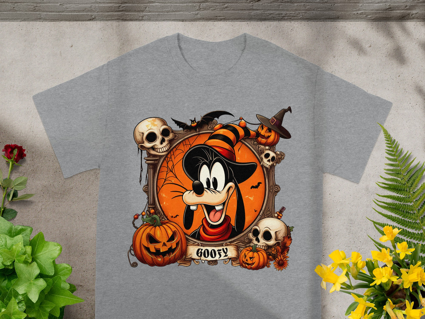 Goofy Halloween graphic with pumpkins, skulls, and a bat on a grey t-shirt.
