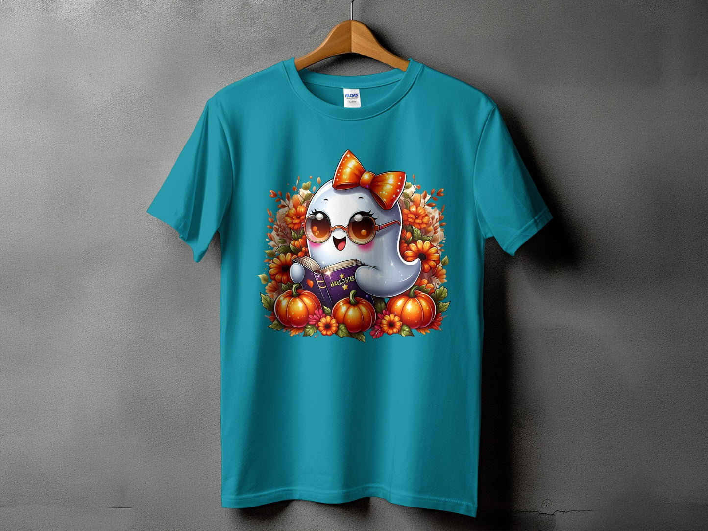 Turquoise t-shirt featuring a cartoon ghost reading a book with pumpkins and flowers.