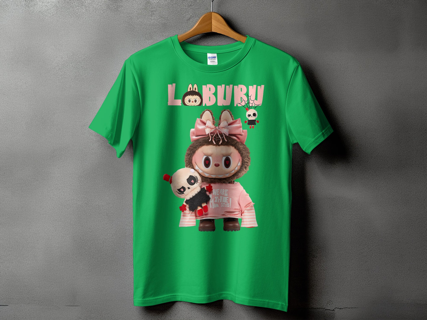 Green t-shirt with cartoon "LABURU" text, character with pink bow, and panda plush.
