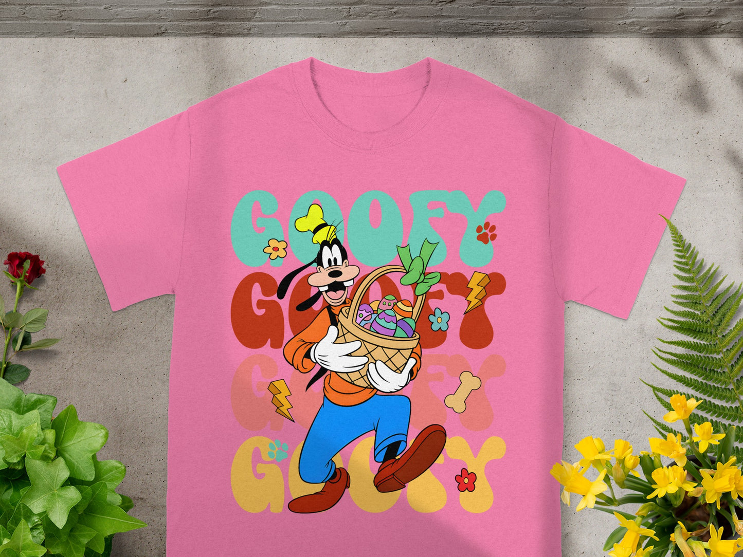 Pink t-shirt featuring Goofy holding an Easter basket with colorful eggs and flowers.