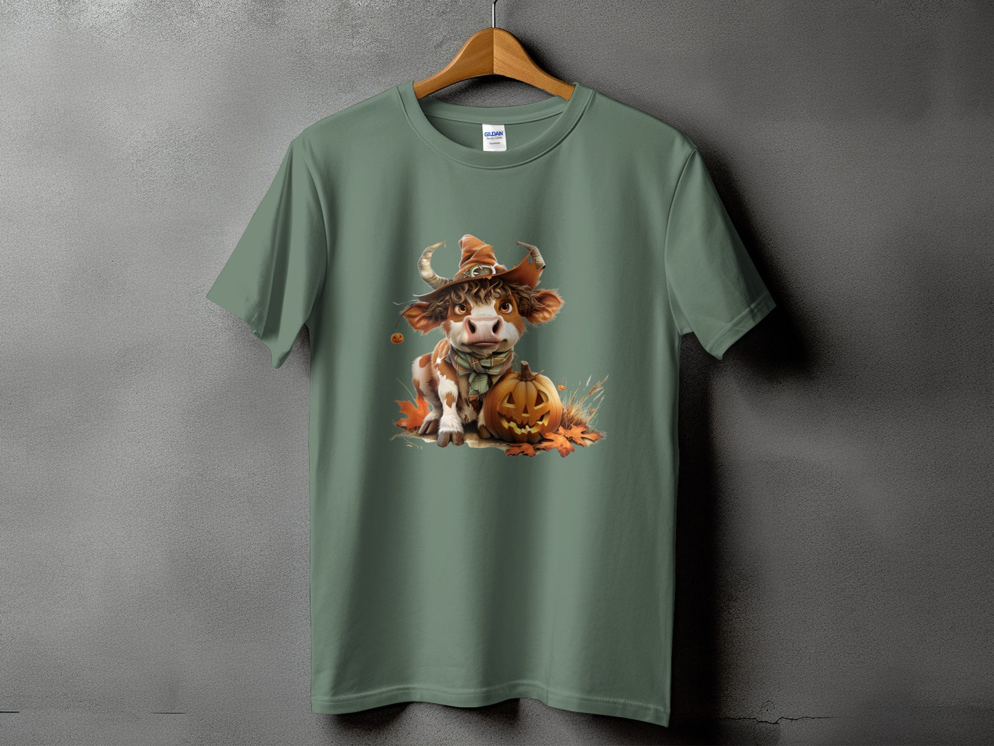 Cow in witch hat with pumpkin and autumn leaves graphic on green t-shirt.