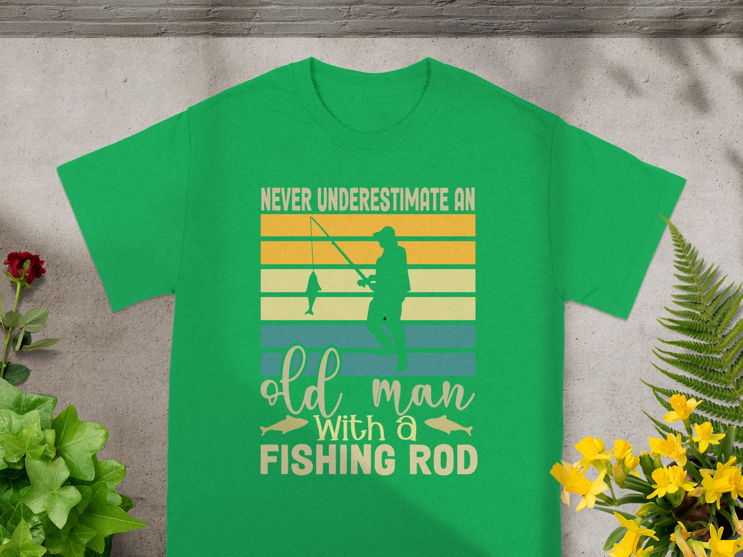 Green t-shirt with text "Never underestimate an old man with a fishing rod" and graphic.