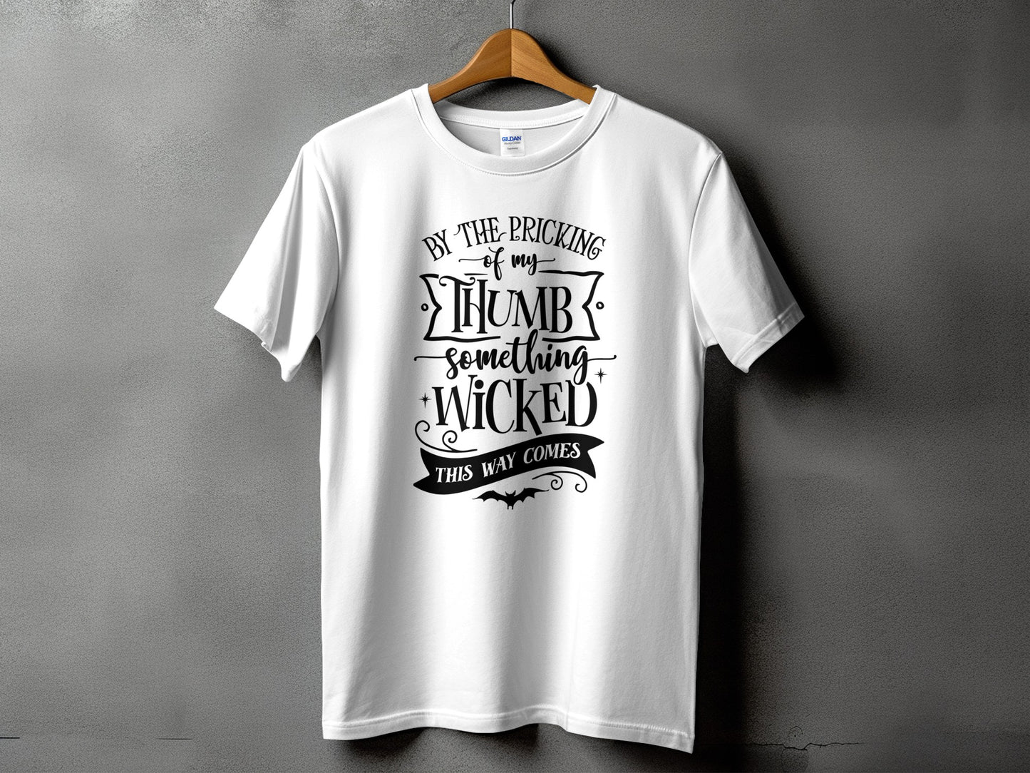 White t-shirt with text "By the pricking of my thumb, something wicked this way comes."