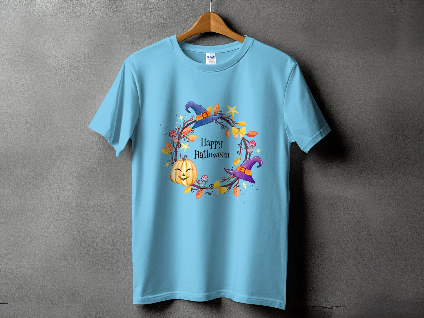 Light blue t-shirt with a watercolor Halloween wreath design featuring a pumpkin and witch hats.