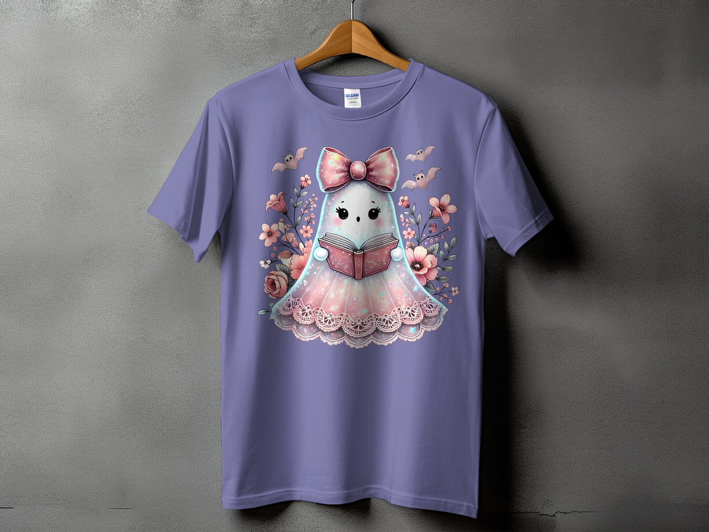 Purple t-shirt with a cute ghost reading a book surrounded by flowers and bats.