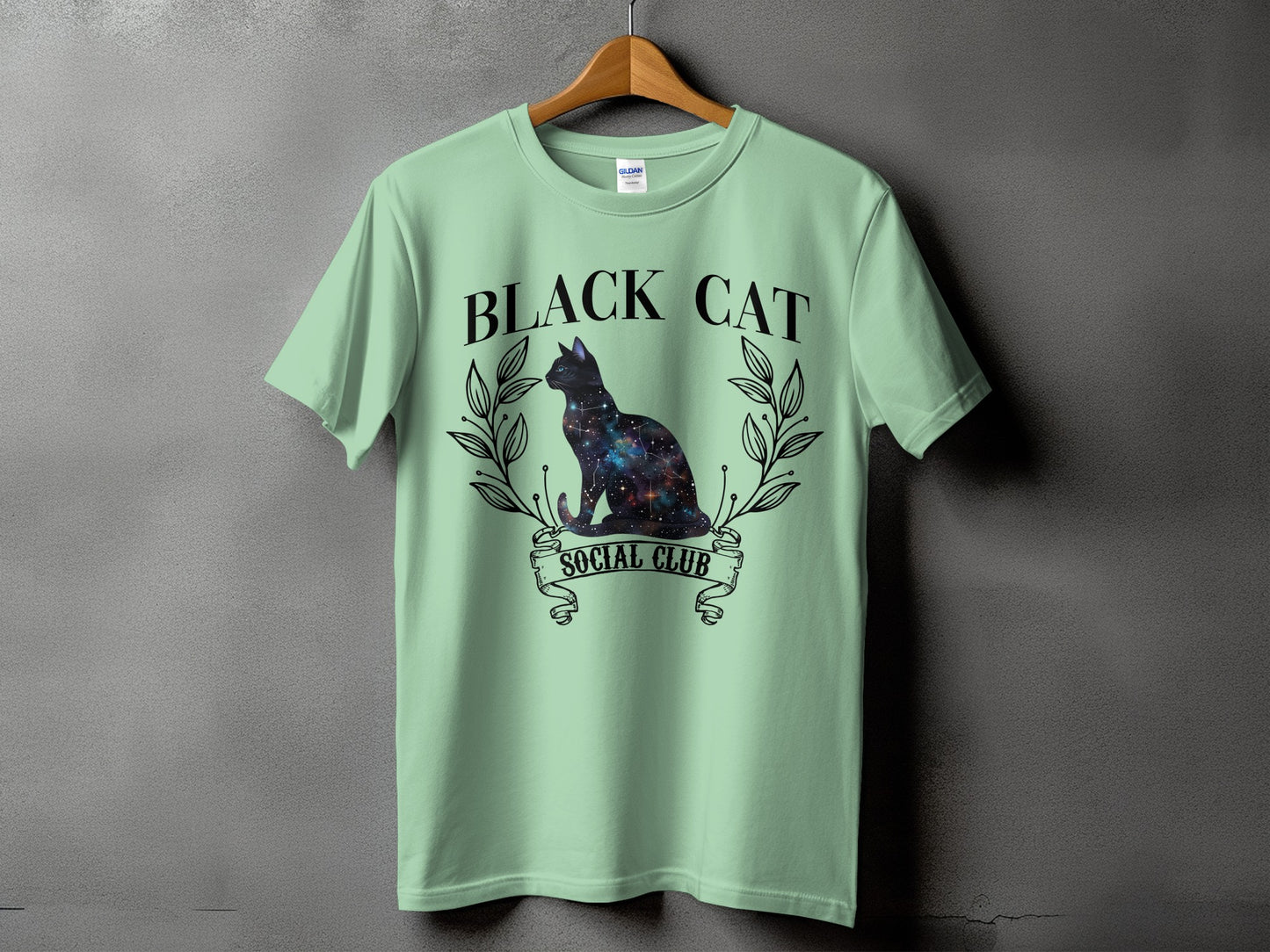 Light green t-shirt with a galaxy-filled black cat and text "BLACK CAT SOCIAL CLUB".