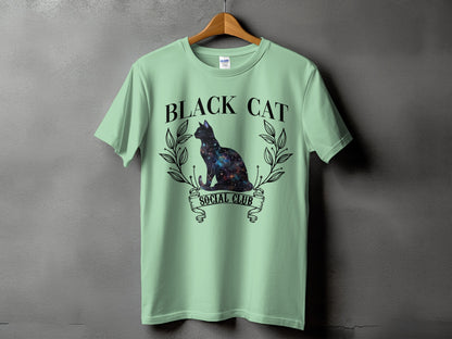 Light green t-shirt with a galaxy-filled black cat and text "BLACK CAT SOCIAL CLUB".