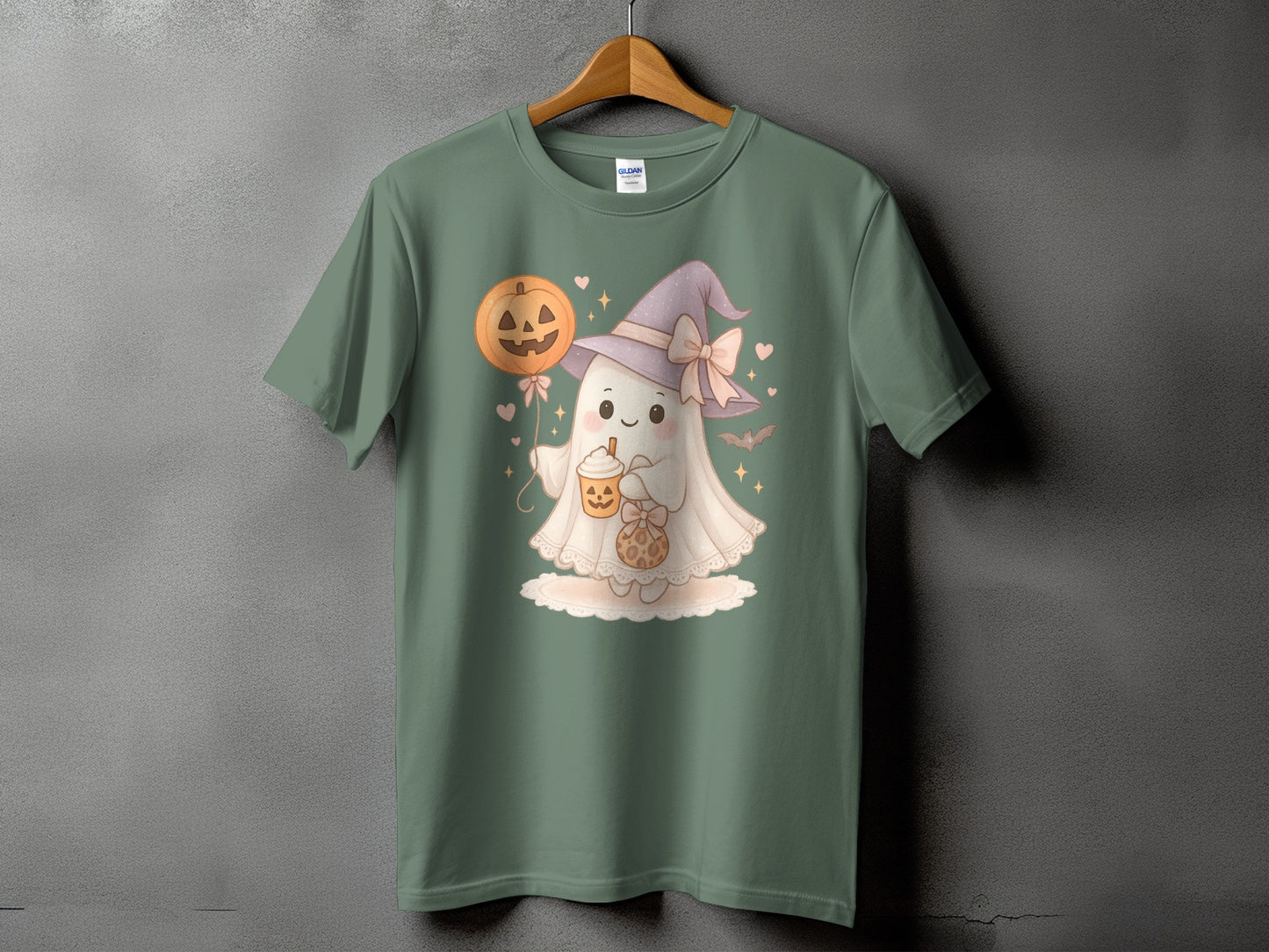 Green t-shirt with a cute ghost wearing a witch hat and holding a pumpkin balloon and drink.