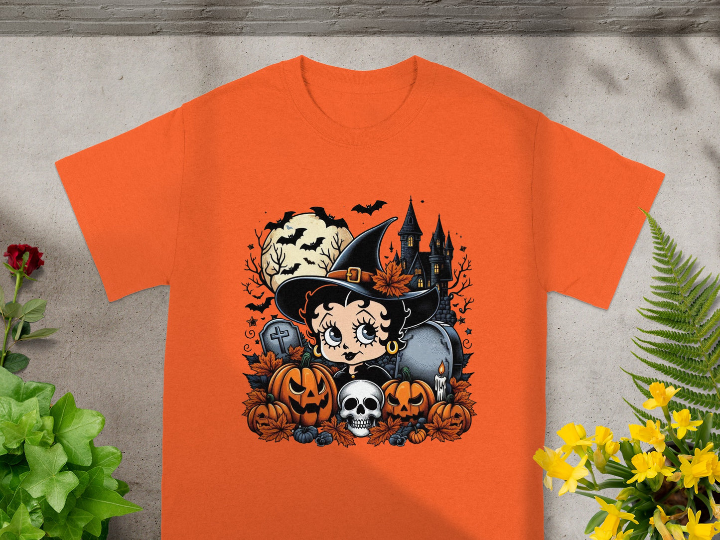 Betty Boop as a witch with Halloween pumpkins, skull, haunted house, and bats.