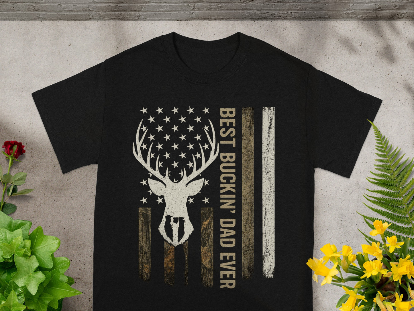 Black t-shirt with a deer skull, stars, and American flag stripes saying "BEST BUCKIN' DAD EVER".
