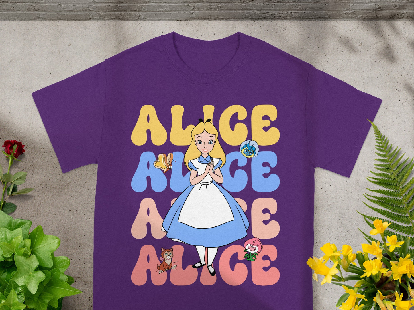 Purple t-shirt with Alice in Wonderland characters and text.
