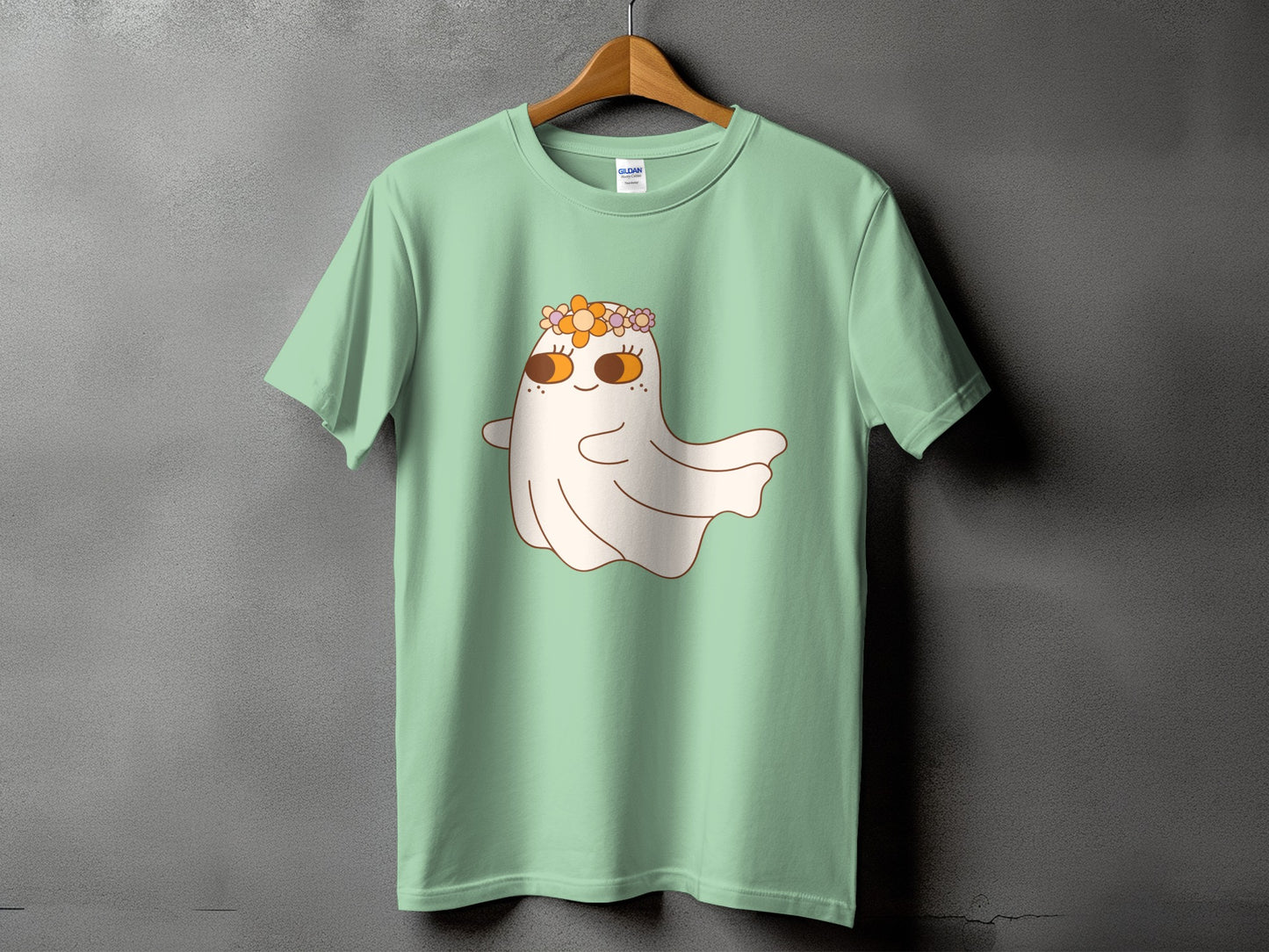 Mint t-shirt with a cartoon ghost wearing a flower crown and sporting orange eyes.