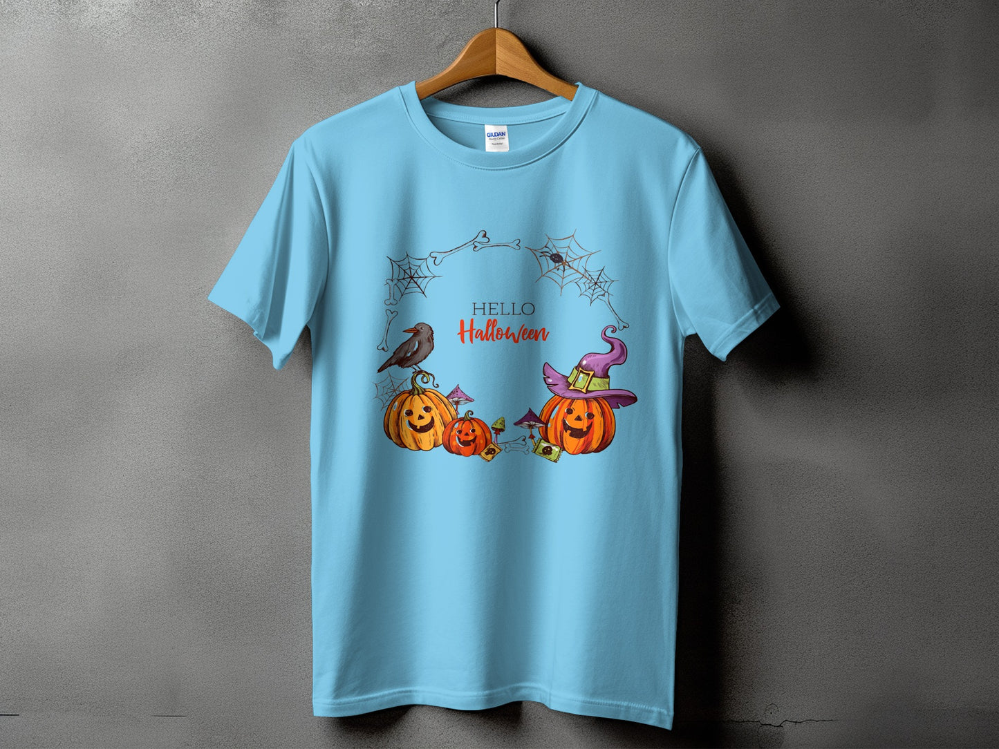 Light blue t-shirt with Halloween graphic of pumpkins, bird, witch hat, and spiders.