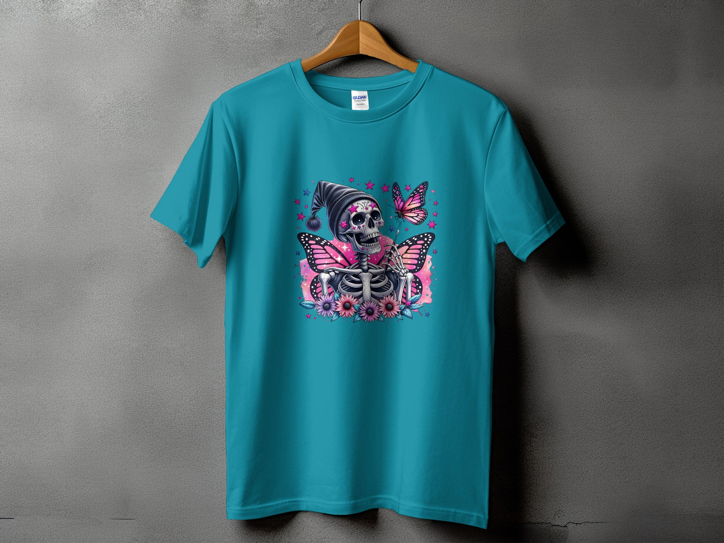 Teal t-shirt with a skeleton wearing a hat, surrounded by butterflies and flowers.