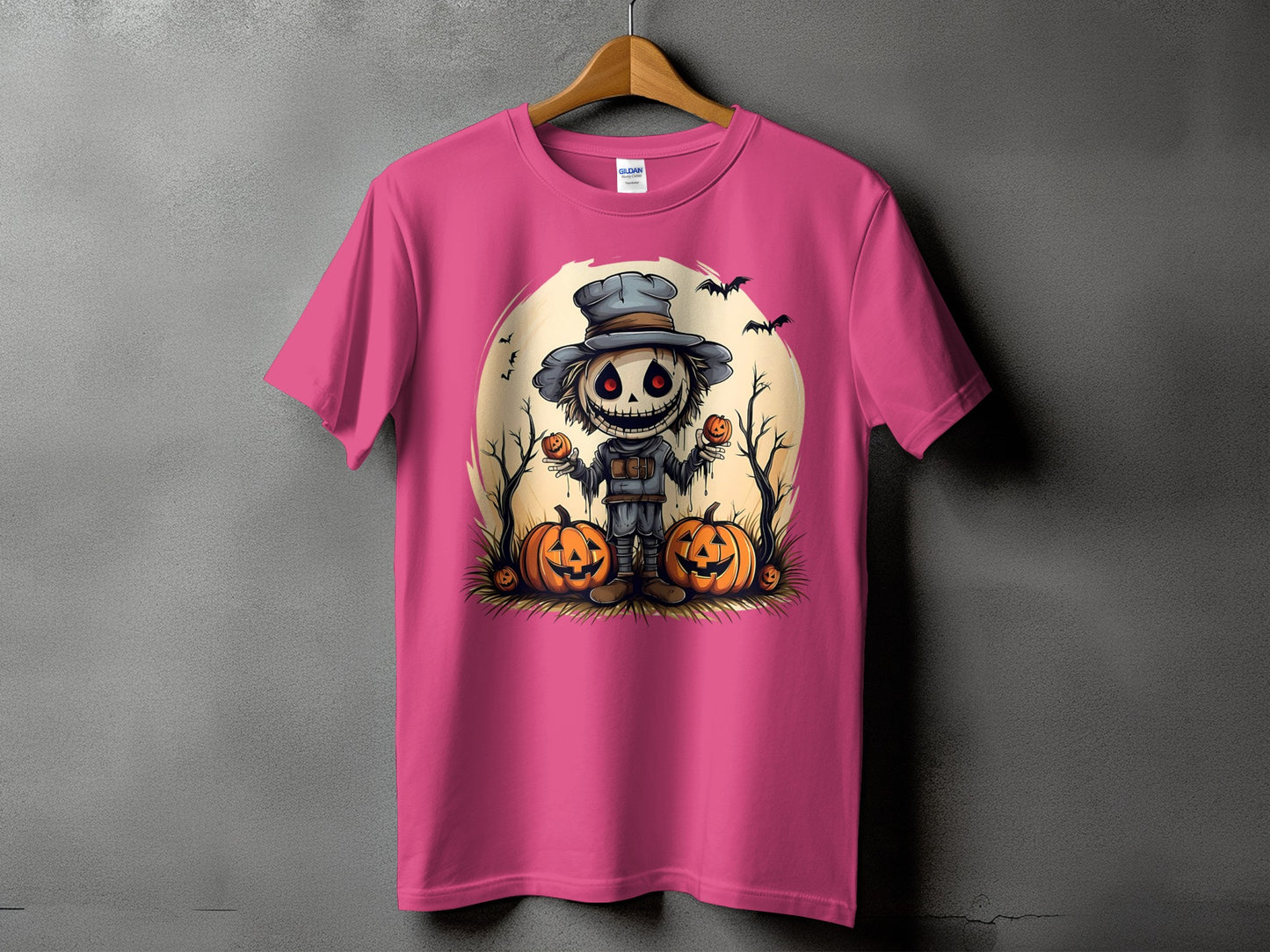 Pink t-shirt with a Halloween scarecrow, pumpkins, bats, and full moon graphic.
