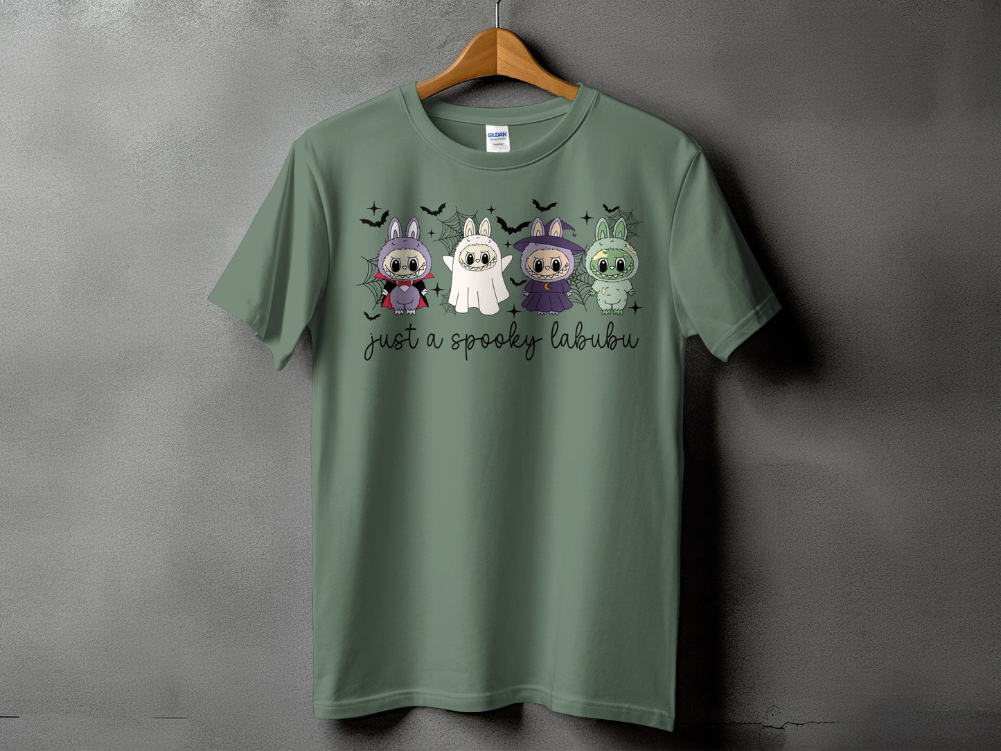 Green t-shirt with "just a spooky labubu" text and four Halloween-themed cartoon creatures.