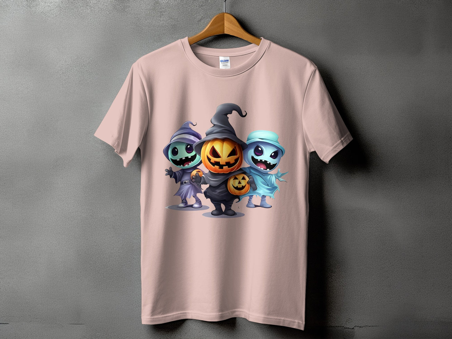 Pink t-shirt featuring three cartoon Halloween characters: a witch, a jack-o'-lantern, and a ghost.