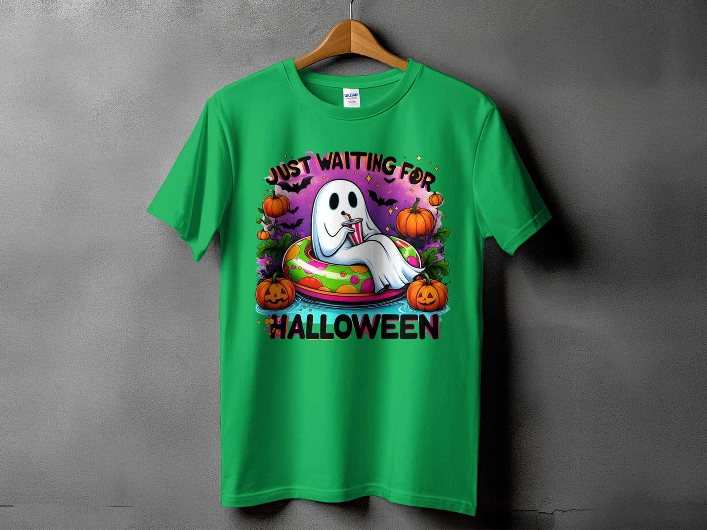 Green t-shirt with a ghost in an inner tube, pumpkins, bats, and text "JUST WAITING FOR HALLOWEEN".
