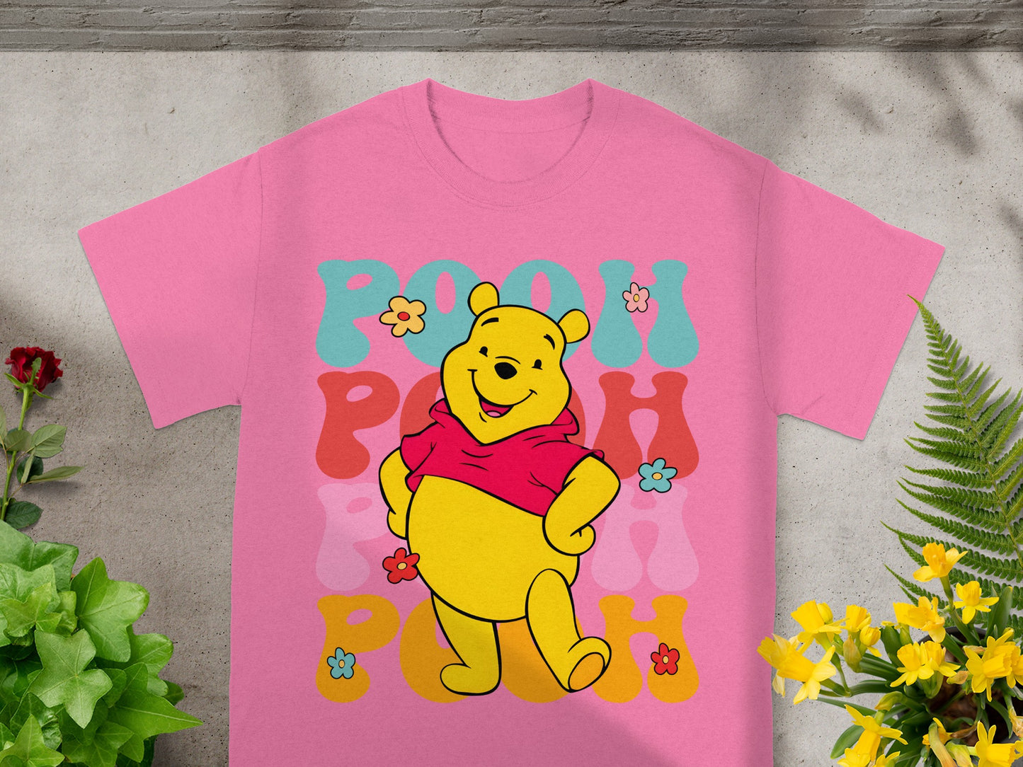 Winnie the Pooh graphic on a pink t-shirt with floral accents.