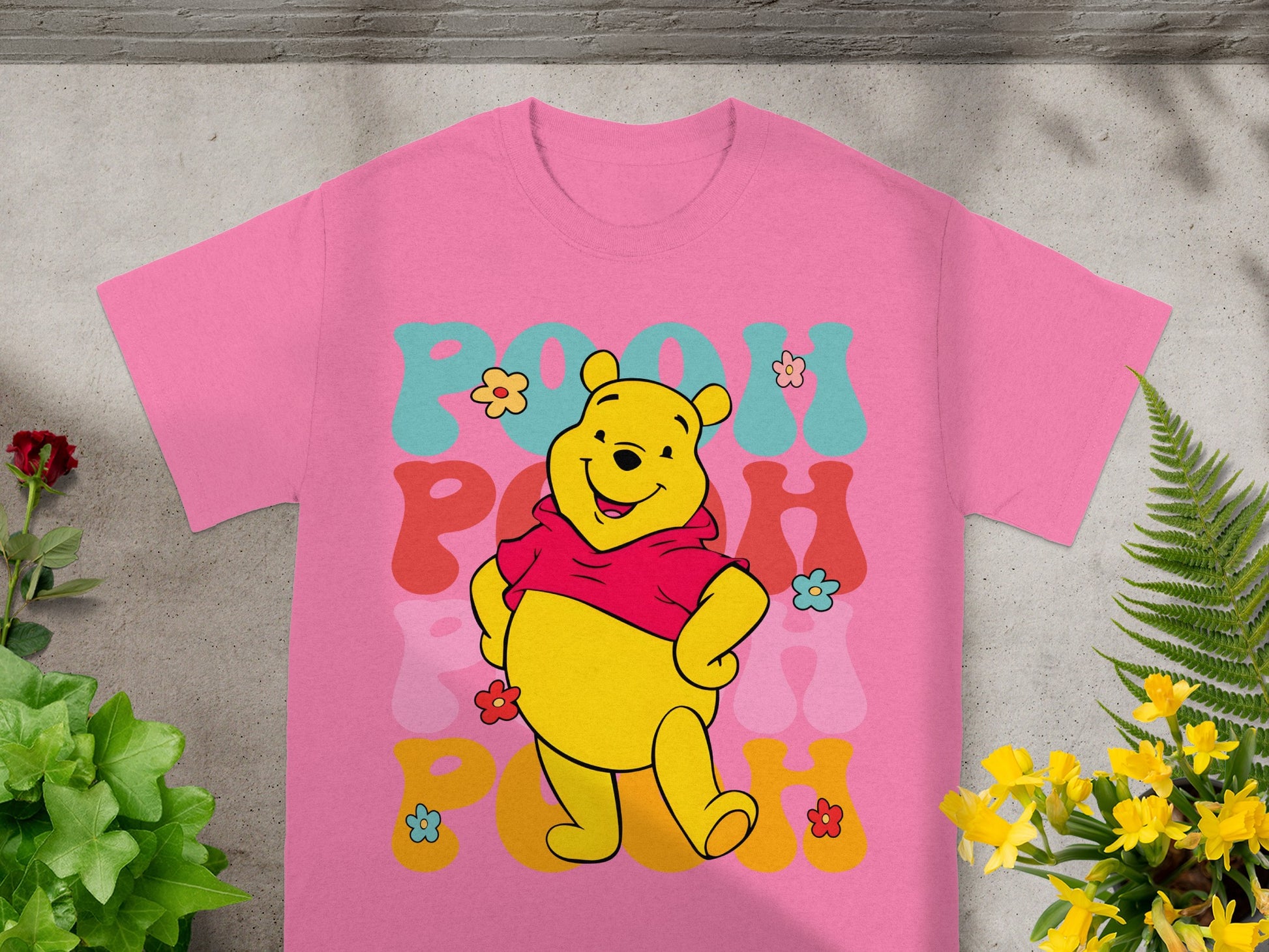 Winnie the Pooh graphic on a pink t-shirt with floral accents.
