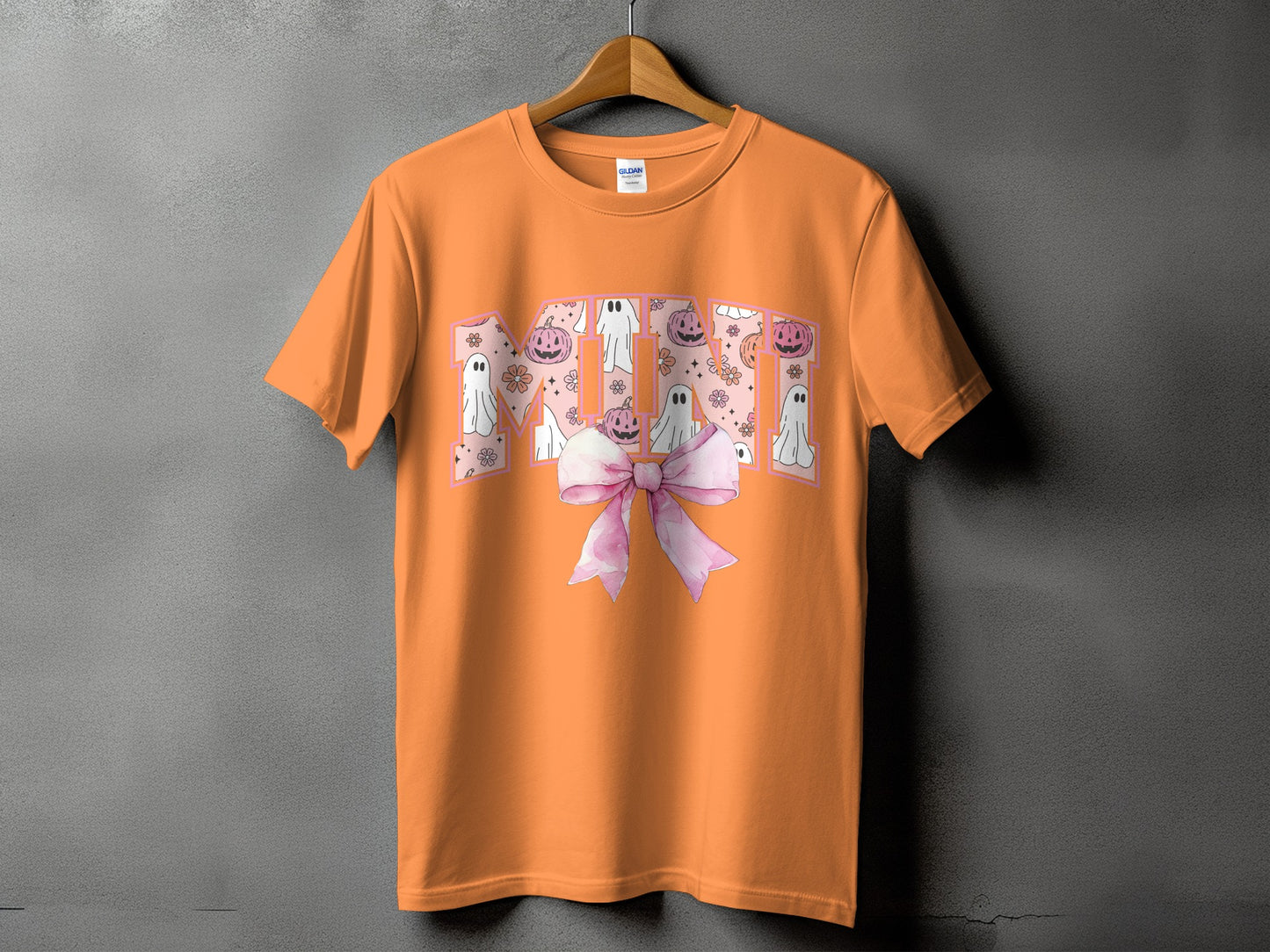 Orange t-shirt with "Mini" in pink arched lettering filled with ghosts and pumpkins.