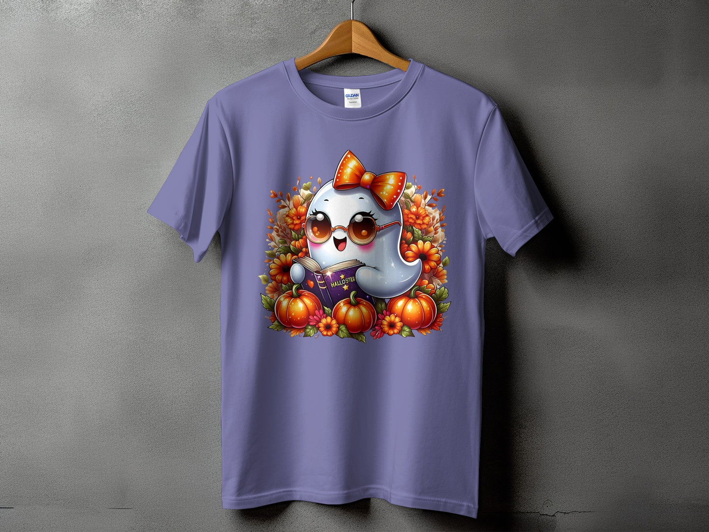Cute ghost reading a book surrounded by pumpkins and flowers on a purple t-shirt.